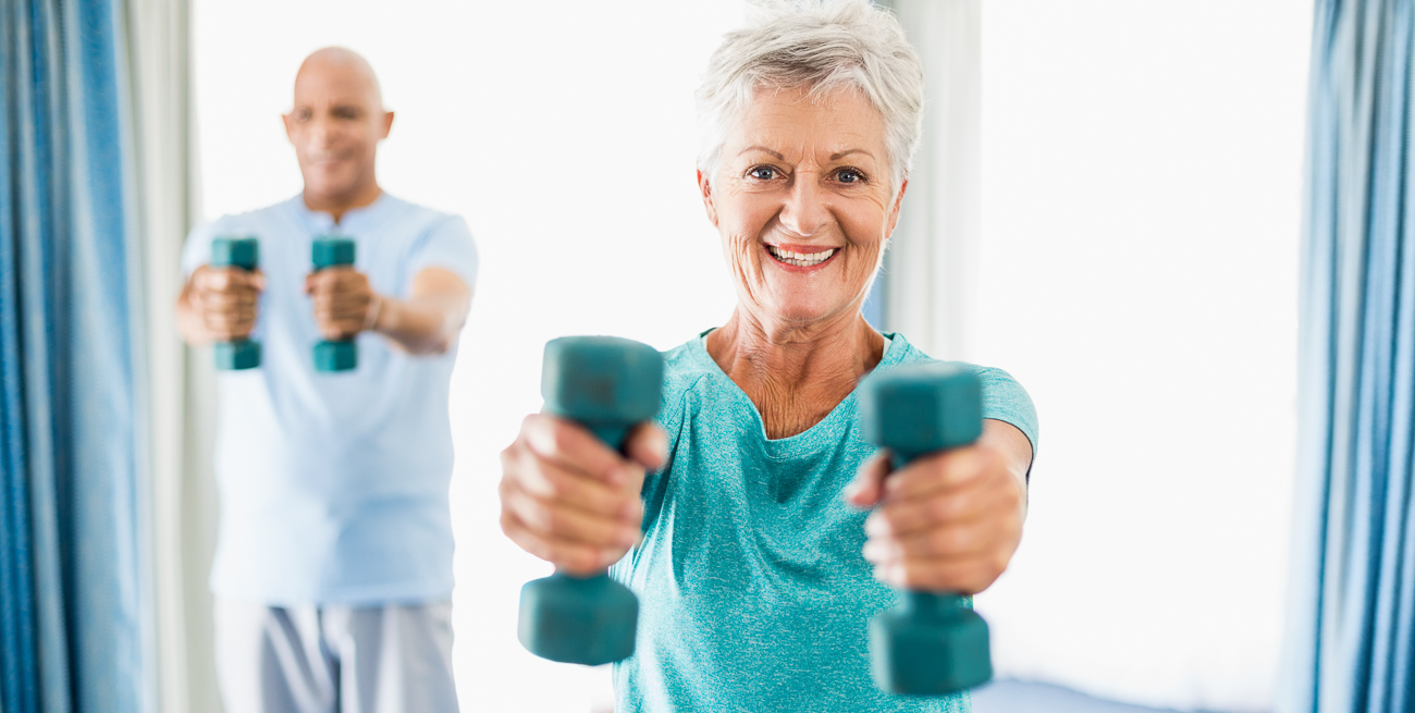 senior man and woman holding dumbbells out